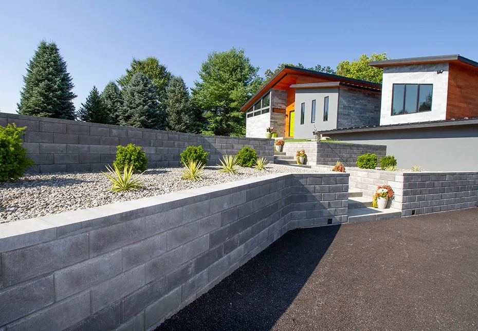 A granite‑tone multi-level retaining wall system, featured in project photos.