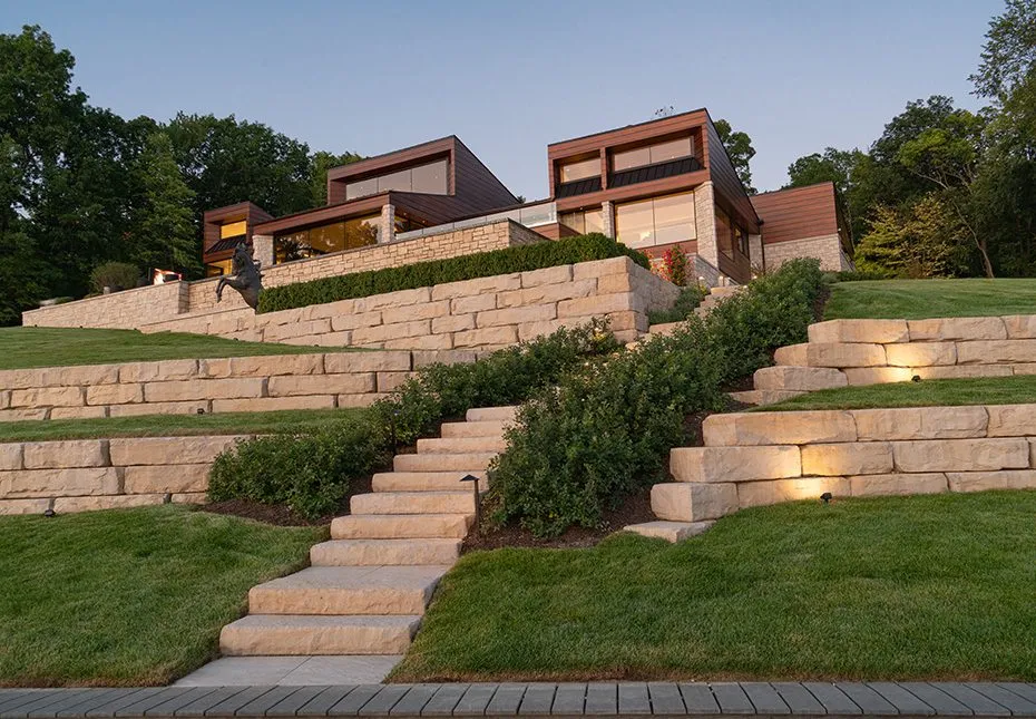 Backyard outdoor living scene with tan retaining walls and steps; warm evening ambiance.