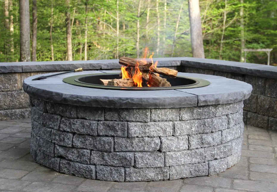 A round stone fire pit with coping in granite tone at a residence, featured in project photos.